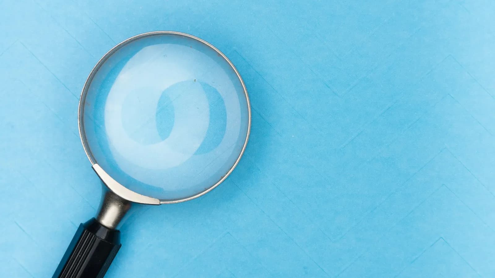 A magnifying glass lying on a light blue surface