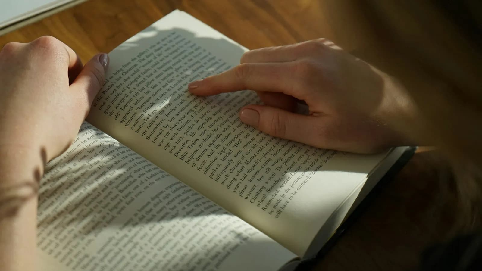 An open book on a table, a reader following the lines