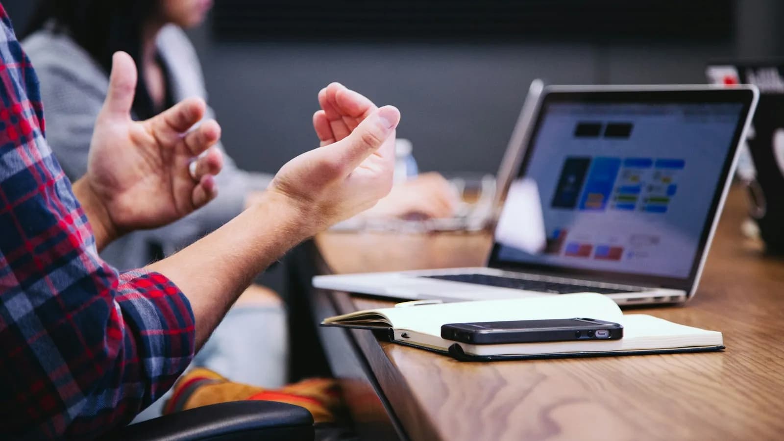 A person explaining something with open hands during a meeting at a laptop