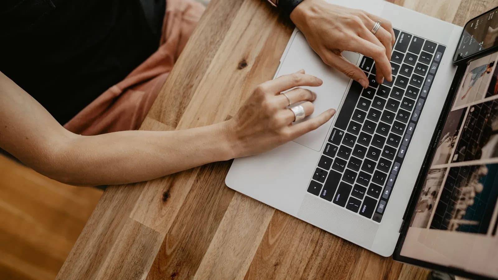 Hands typing on a laptop on a wooden table