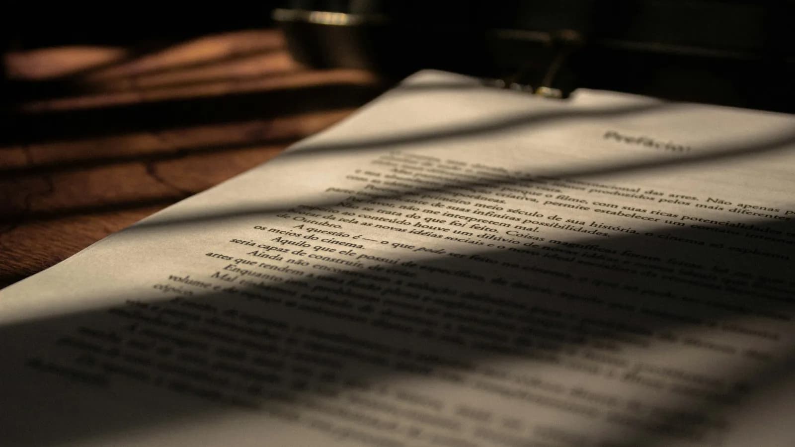 Close-up of a printed page of text lying on a wooden table in warm light