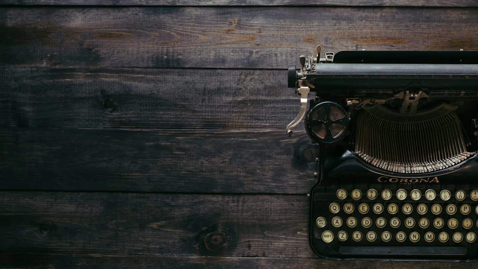 A black vintage typewriter on a dark wooden surface